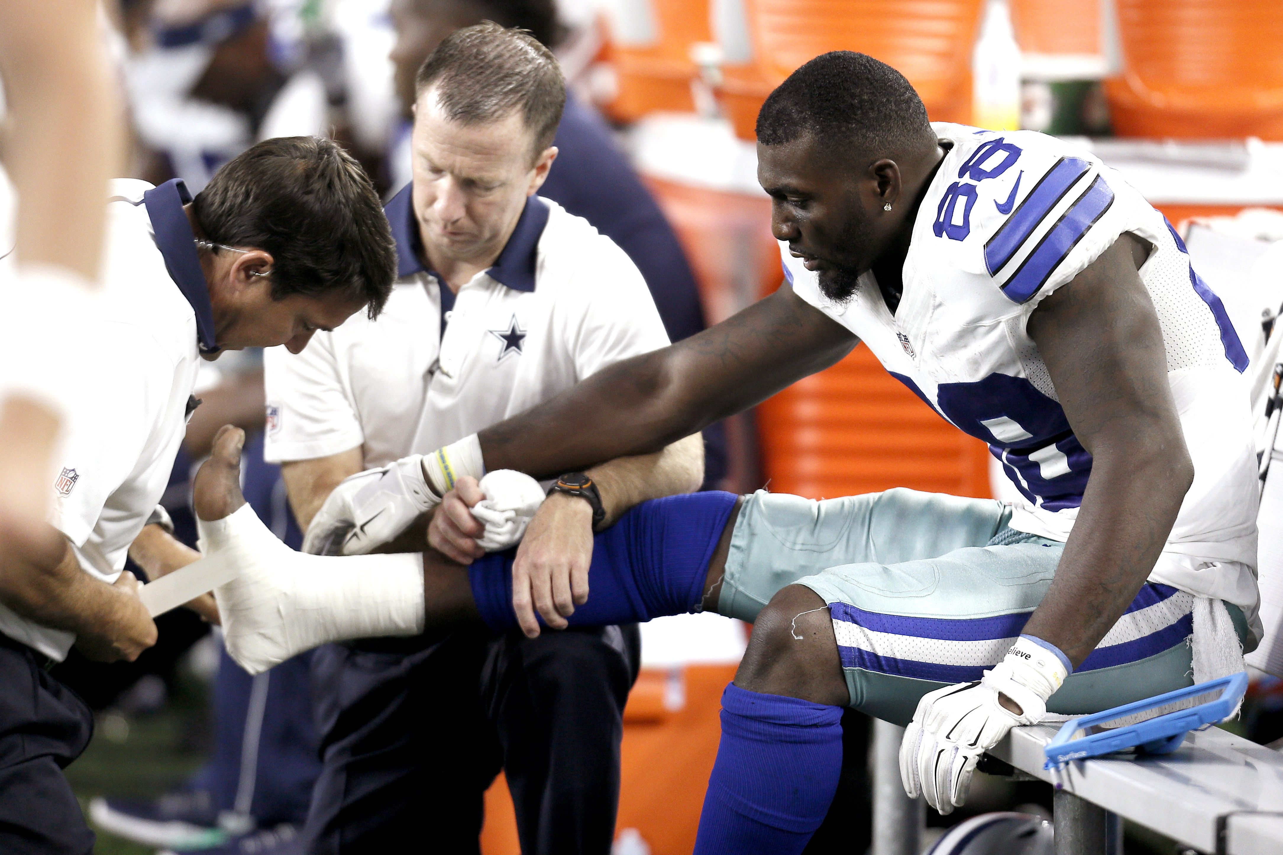 Dallas Cowboys wide receiver Dez Bryant (88) is tended to on the sideline after injuring his foot during the second half of an NFL football game against the New York Giants Sunday, Sept. 13, 2015, in Arlington, Texas. (AP Photo/Brandon Wade)